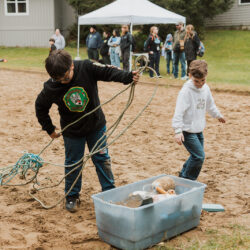 two kids hold old blue fishing rope ie. marine debris