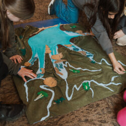 Children play felt logs onto felt map of the watershed