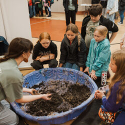 volunteer shows group of students soil being help in plastic kiddie pool